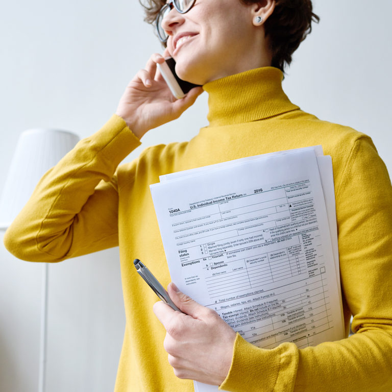 Woman on Cellphone Smiling holding Paperwork