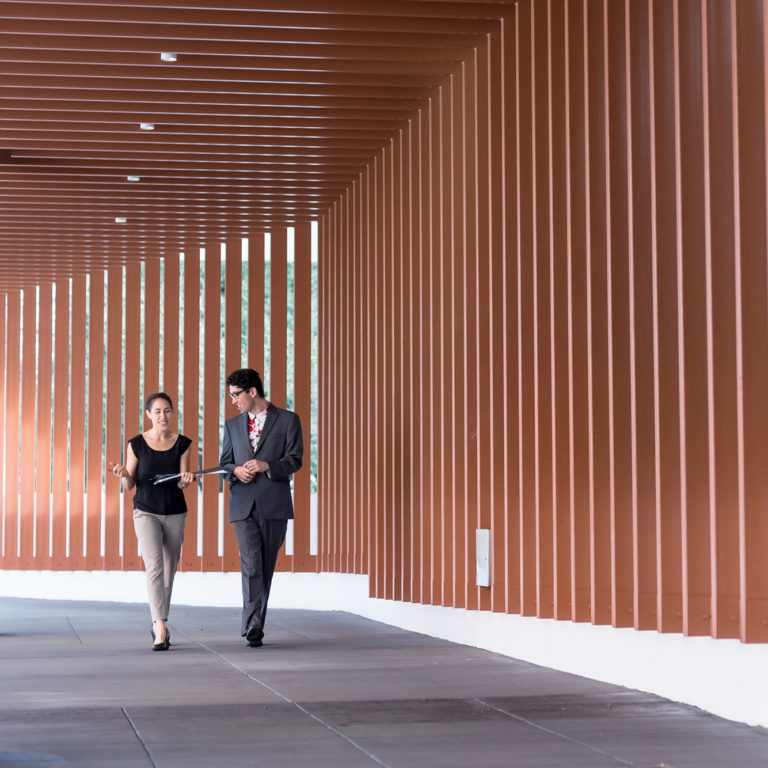 Man and a woman walking and talking through wooden corridor